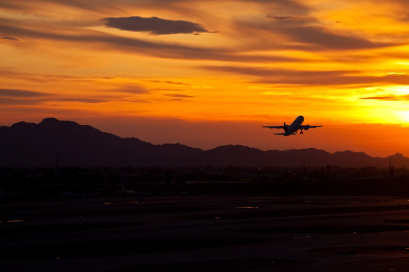 Plane taking off into red sunset.